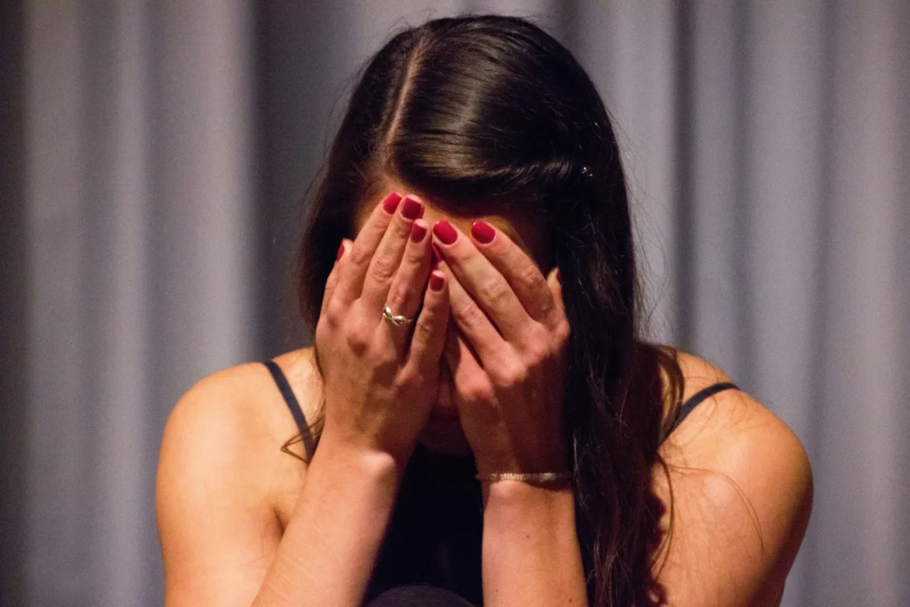 Trauma woman covering face julia taubitz tZqYudVcsP0 unsplash copy